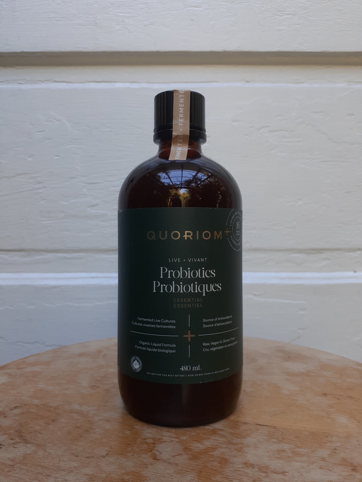 Bottle of Guorion Probiotics on a wooden surface with a white wall background